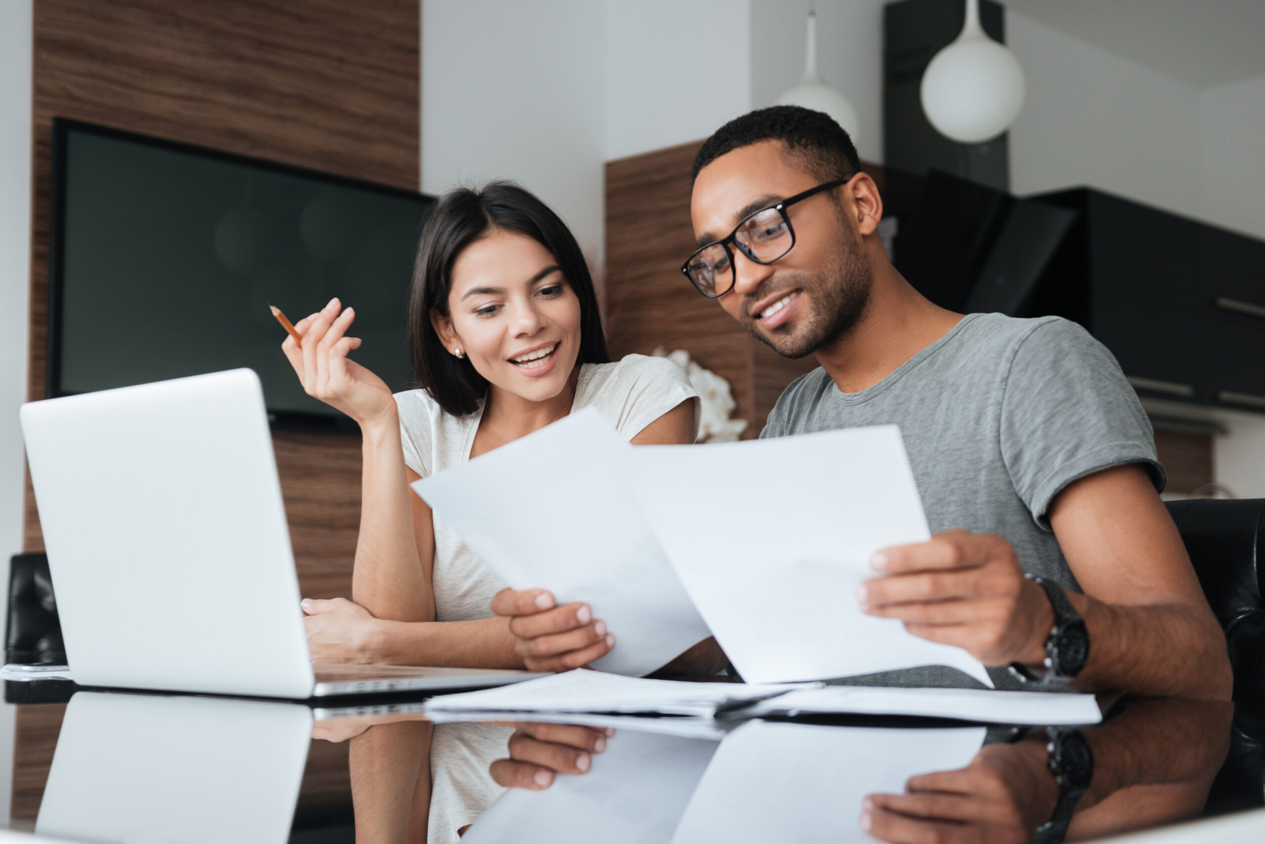 graphicstock photo of cheerful loving young couple using laptop and analyzing their finances with documents look at papers r8sI1YQ hx scaled